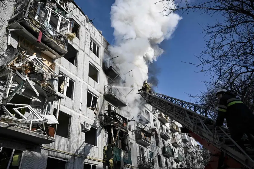 Firefighters work to extinguish a blaze after a shell struck a building in the town of Chuguiv in eastern Ukraine