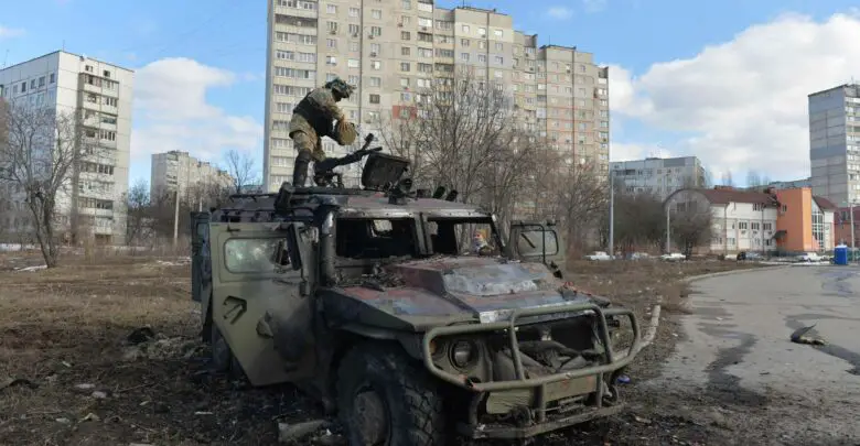 A Ukrainian Territorial Defense fighter examines a destroyed Russian infantry mobility vehicle GAZ Tigr after the fight in Kharkiv