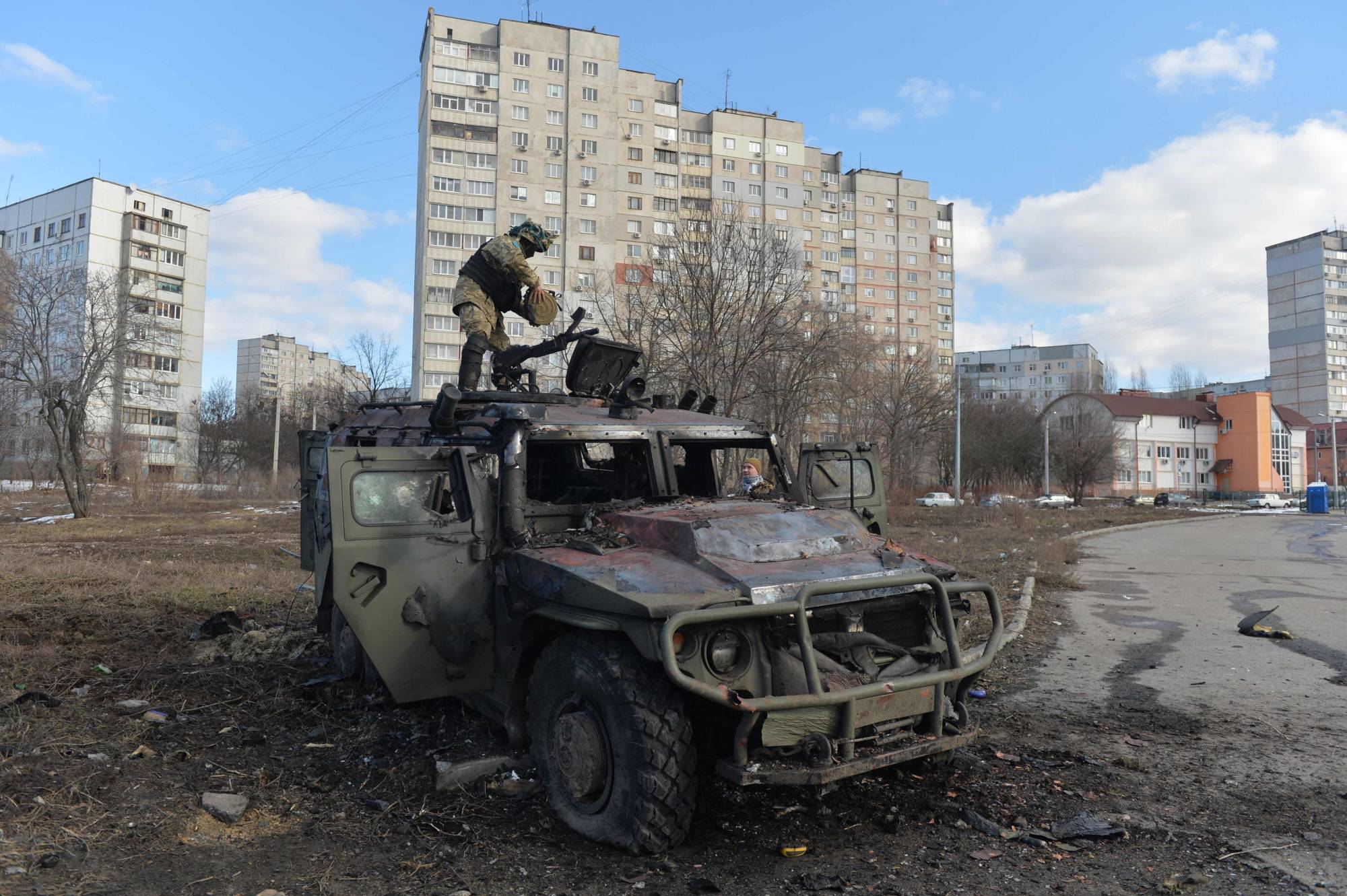 A Ukrainian Territorial Defense fighter examines a destroyed Russian infantry mobility vehicle GAZ Tigr after the fight in Kharkiv