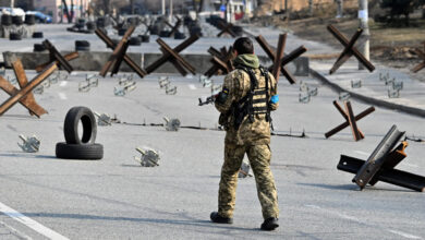 A Ukrainian soldier passes by anti-tank protection elements as he stands guard at a checkpoint