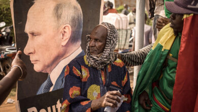 A man sits near a portrait of Russian President Vladimir Putin during a demonstration in Bamako, Mali