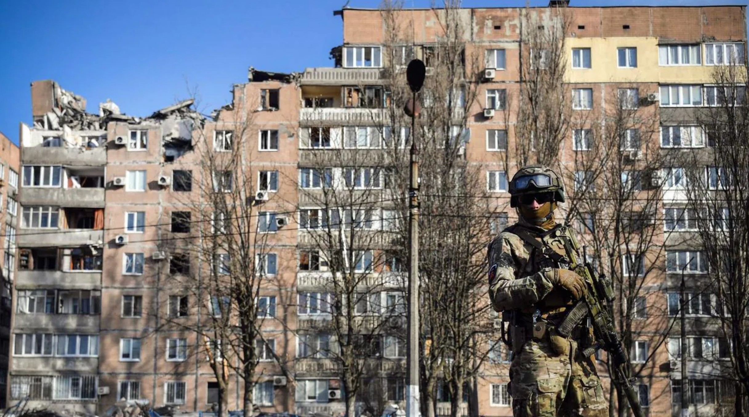 A Russian soldier outside a damaged apartment building in Donetsk