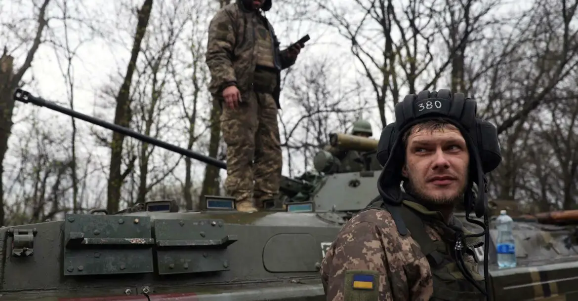 Ukrainian soldiers stand next to their armored personnel