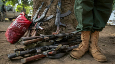 A former child soldier stands next to rifles during the release ceremony for child soldiers in Yambio, South Sudan