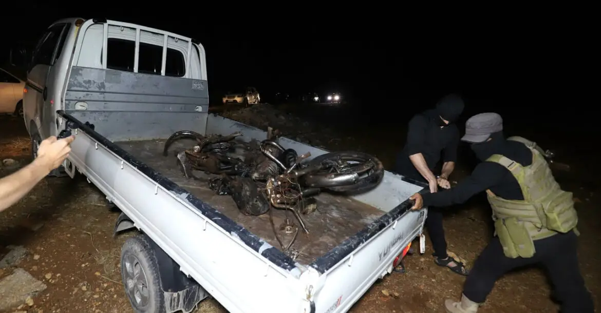 Fighters of jihadist group Hayat Tahrir al-Sham, which dominates northwestern Syria, carry away a mangled motorcyle after a US drone strike targeting a leader of a rival, Al-Qaeda-linked faction, Hurras al-Deen
