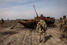 Ukrainian soldiers stand by a burnt Russian tank on the outskirts of Kyiv, on 31 March, 2022