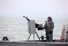A Ukrainian serviceman standing guard as he boat patrols a water area of Ukraine's Black Sea port of Mariupol