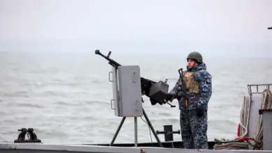 A Ukrainian serviceman standing guard as he boat patrols a water area of Ukraine's Black Sea port of Mariupol