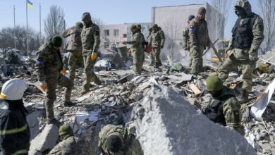 Ukrainian soldiers search for bodies in the debris at the military school hit by Russian rockets the day before, in Mykolaiv, southern Ukraine