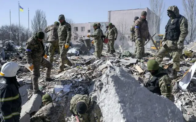 Ukrainian soldiers search for bodies in the debris at the military school hit by Russian rockets the day before, in Mykolaiv, southern Ukraine