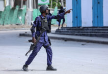 A security officer gestures as he and colleagues patrol at the the site of explosions in Mogadishu