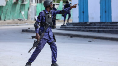 A security officer gestures as he and colleagues patrol at the the site of explosions in Mogadishu