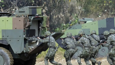 Taiwan soldiers walk behind an armored personnel carrier during an annual military drill in Taichung, central Taiwan