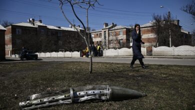 A woman looks at the remains of a missile in Ukraine's Kharkiv