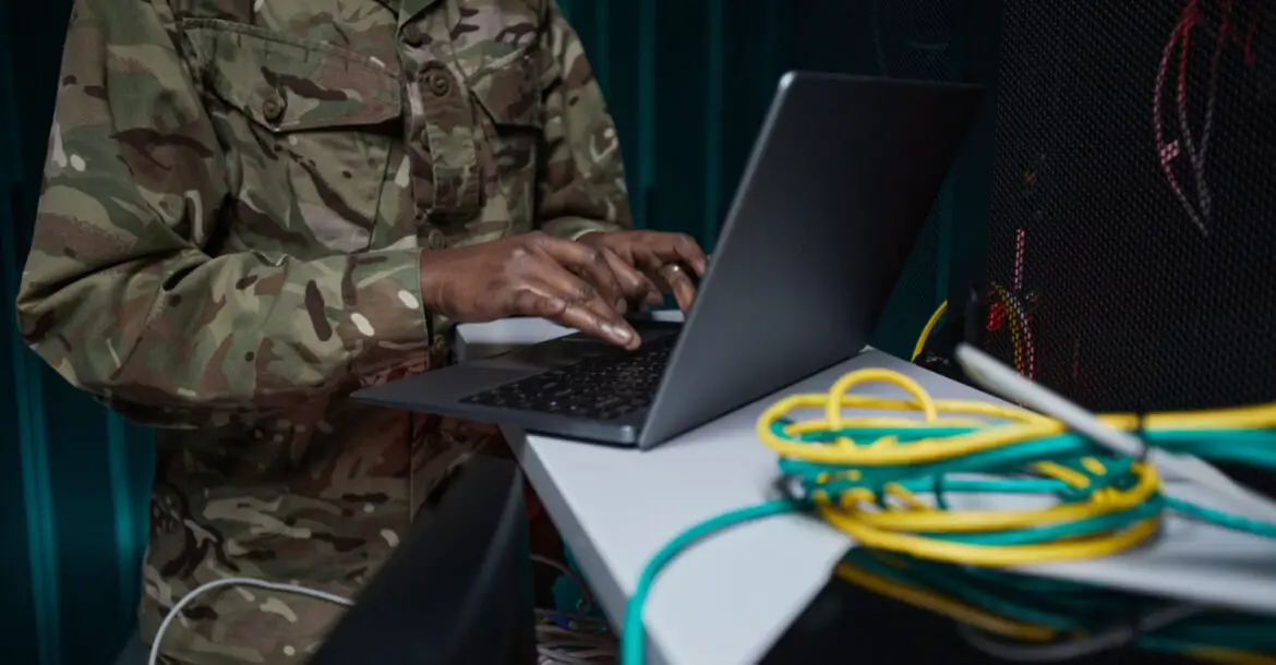 Soldier using laptop in computer server room