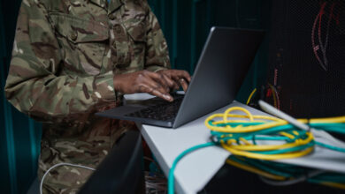 Soldier using laptop in computer server room