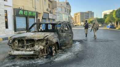 A damaged vehicle is pictured in a street in the Libyan capital Tripoli following clashes between rival local groups