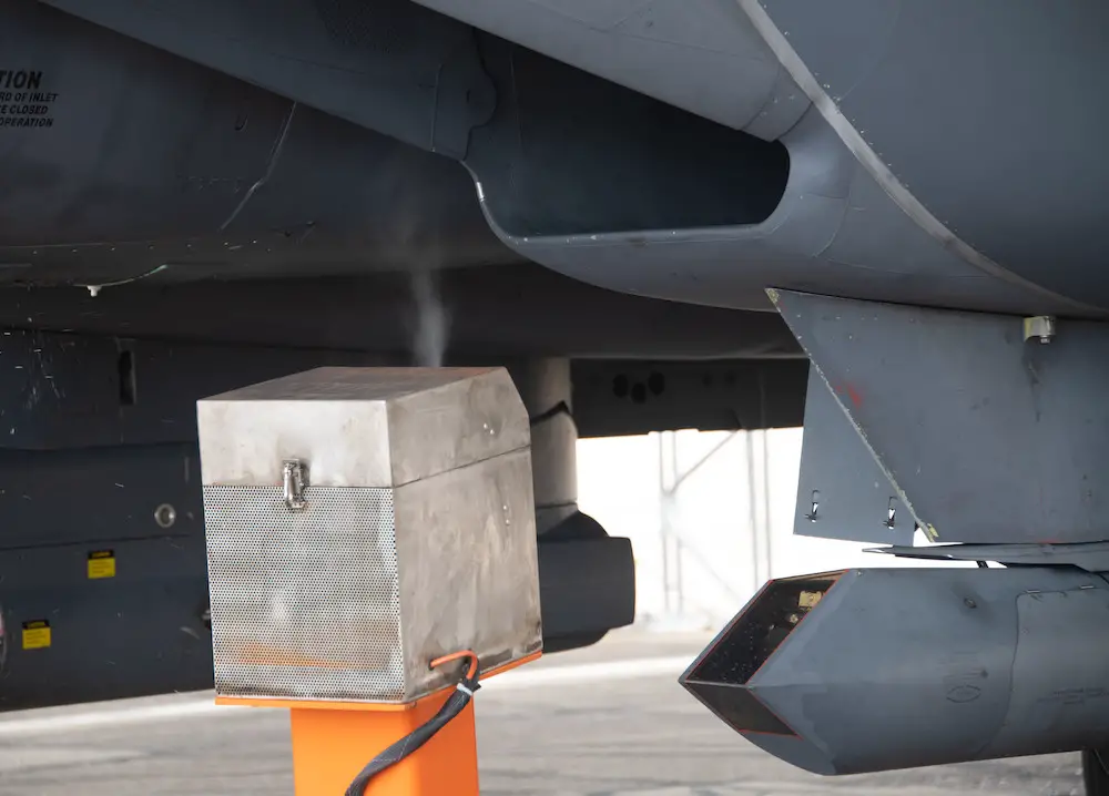 Analysts from the Air Force Research Laboratory use the orange spray carts to insert oil of wintergreen into the idling F-15E Strike Eagle