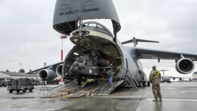 An Army AH-64 Apache helicopter is unloaded from an Air Mobility Command C-5M Galaxy