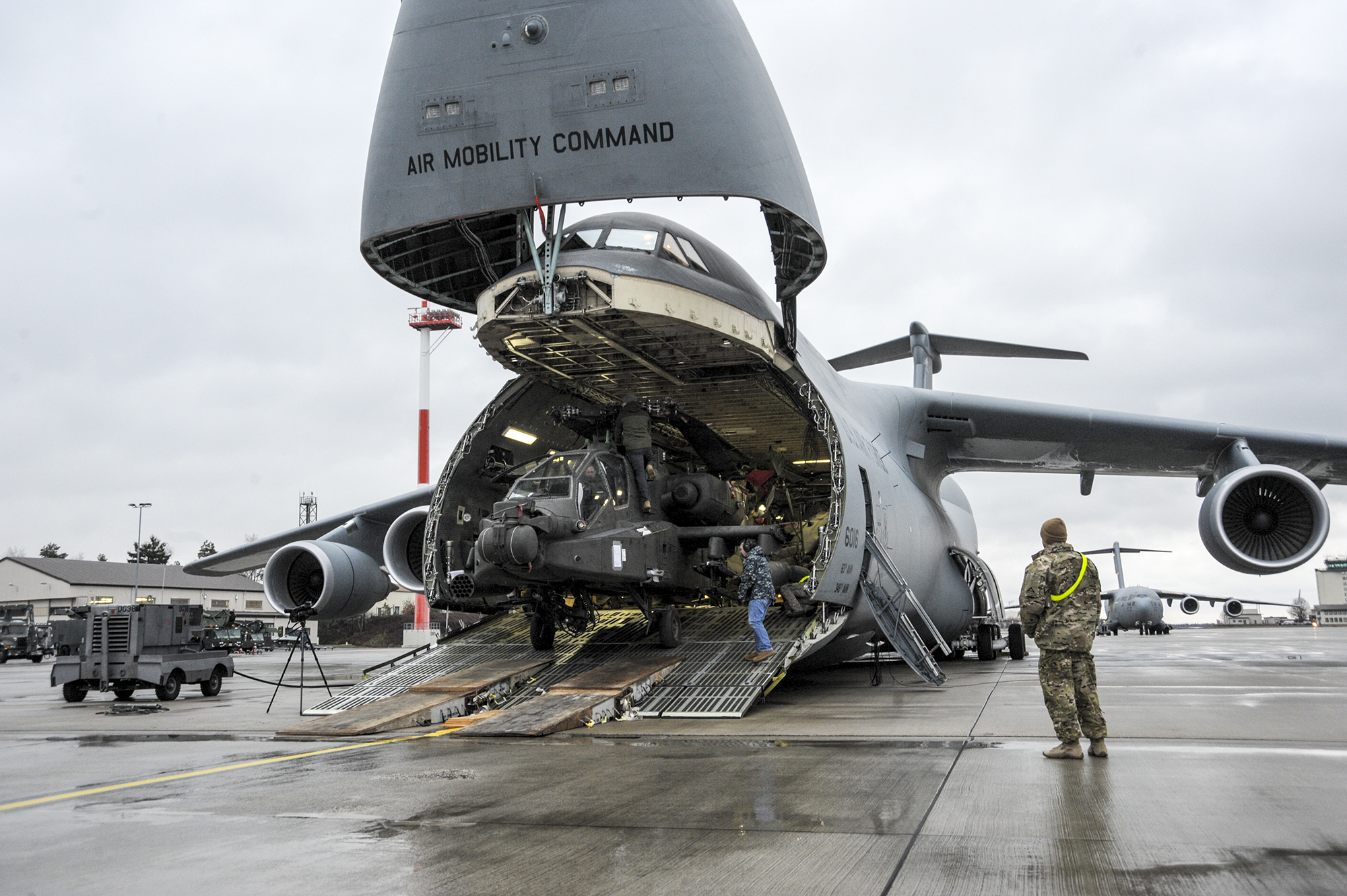 An Army AH-64 Apache helicopter is unloaded from an Air Mobility Command C-5M Galaxy