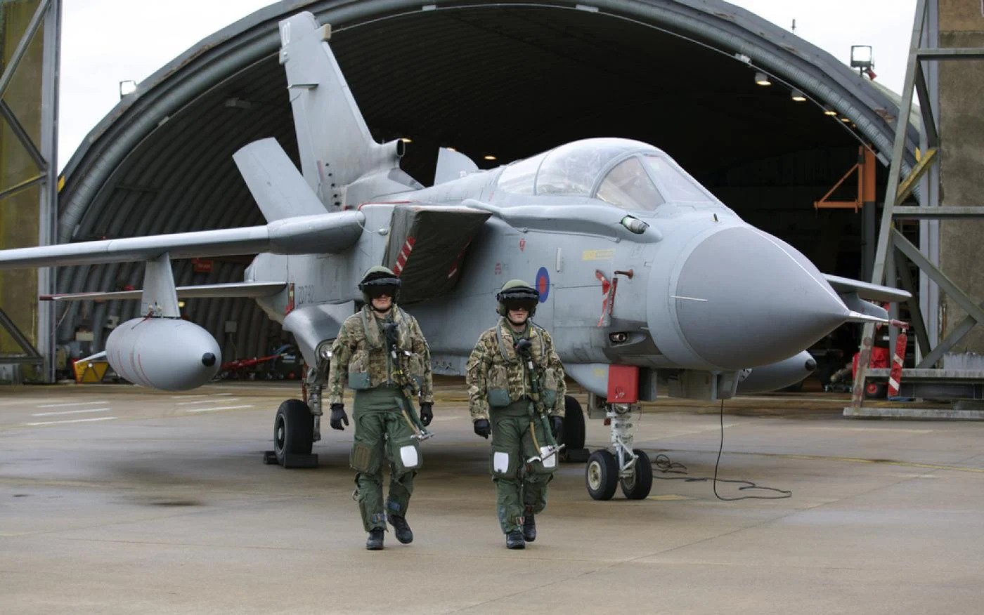 Pilots walk in front of a Tornado GR4 at the British Royal Air Force airbase RAF Marham in Norfolk