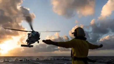 MH-60R helicopter landing on HMAS Hobart at sunset.