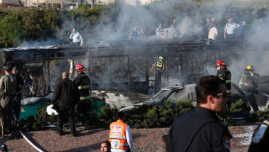 Israeli security forces and emergency services gather around a burned-out bus following the explosion in Jerusalem