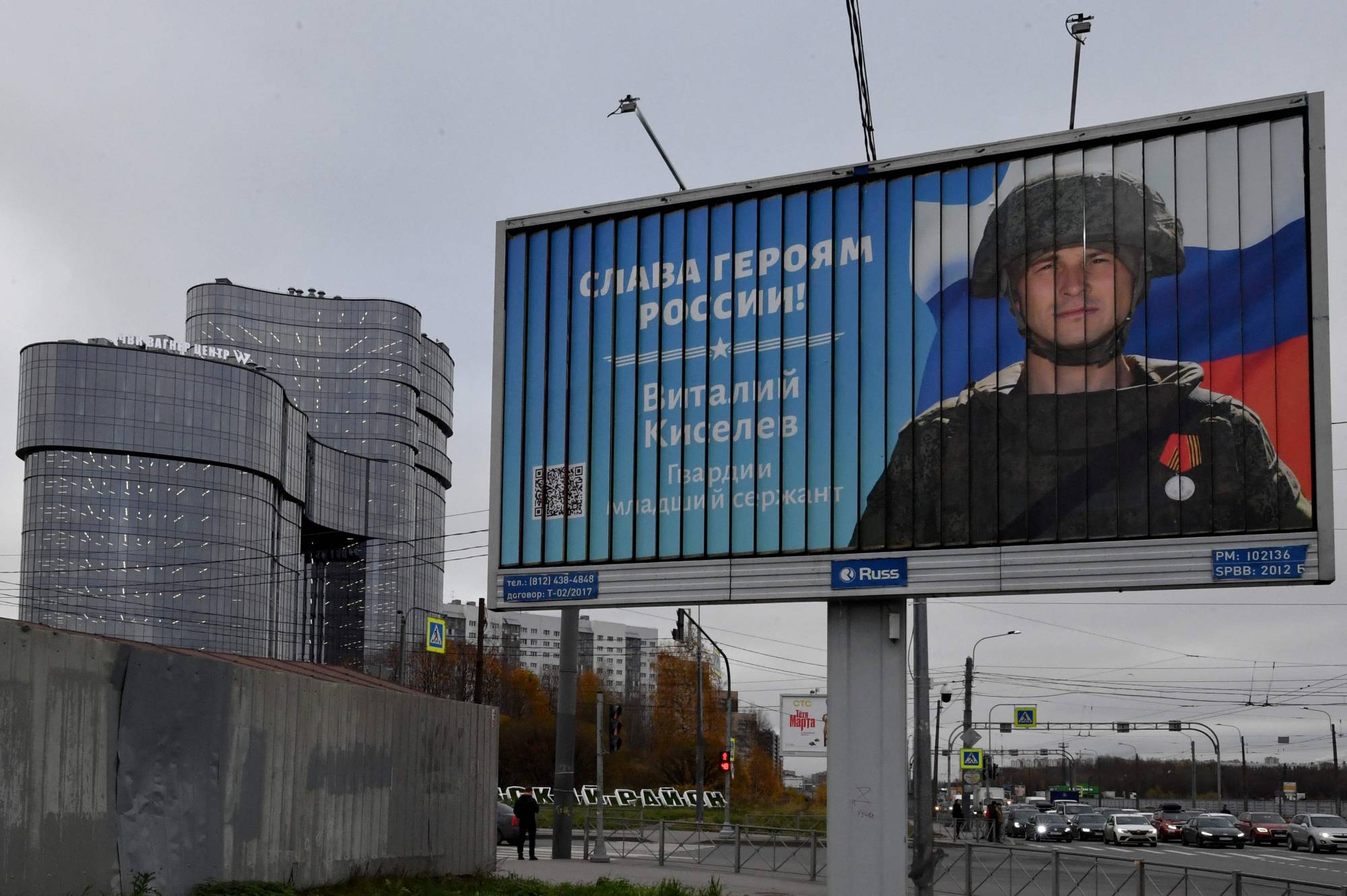 A poster displaying a Russian soldier with a slogan reading "Glory to the Heroes of Russia" is seen on a street side near the PMC Wagner Center