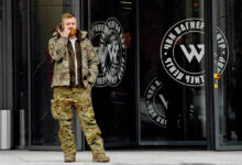 A man wearing military camouflage stands at the entrance of the PMC Wagner Centre, associated with the Wagner Group, in St. Petersburg, Russia