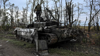 A Ukrainian soldier stands atop an abandoned Russian tank near a village on the outskirts of Izium, in the Kharkiv region, eastern Ukraine