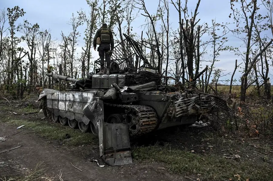 A Ukrainian soldier stands atop an abandoned Russian tank near a village on the outskirts of Izium, in the Kharkiv region, eastern Ukraine