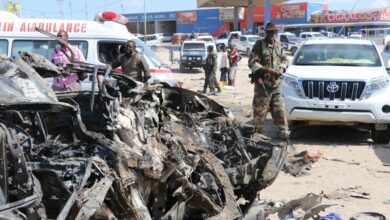 A soldier is seen next to the wreckage of car that was damaged during the suicide attack in Mogadishu