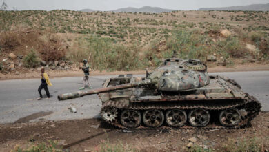 Farmers pass a tank that allegedly belonged to the Eritrean army on a road southwest of the Tigrayan capital, Mekele