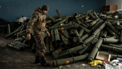 A Ukrainian serviceman stands near a pile of empty mortar shell containers