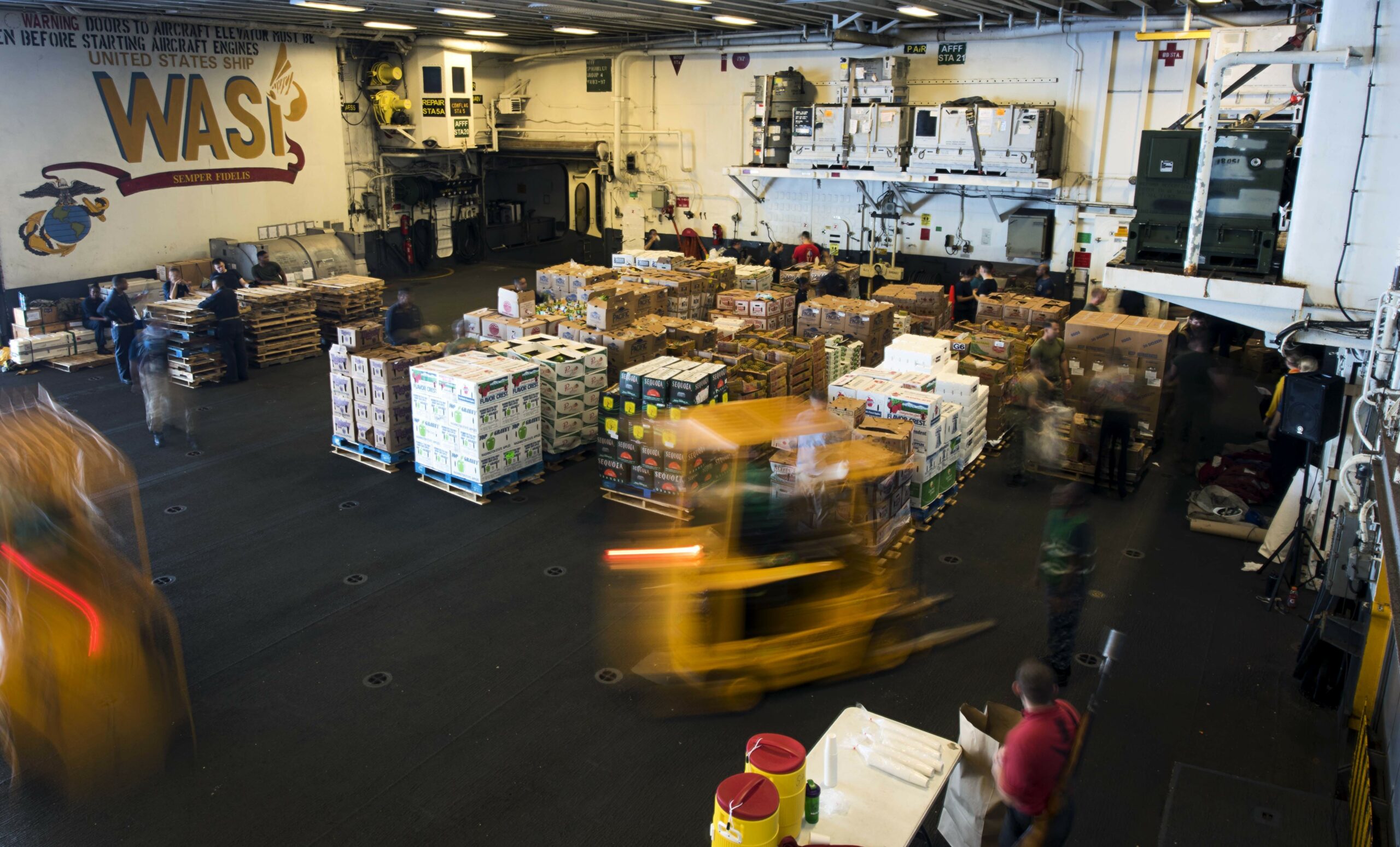 EAST CHINA SEA (Sept. 22, 2018) - Sailors aboard the amphibious assault ship USS Wasp (LHD 1) use forklifts to move food and supplies during a replenishment at sea with the dry cargo and ammunition ship USNS Washington Chambers (T-AKE). Wasp, flagship of the Wasp Amphibious Ready Group, with embarked 31st Marine Expeditionary Unit, is operating in the Indo-Pacific region to enhance interoperability with partners and serve as a ready-response force for any type of contingency. (U.S. Navy photo by Mass Communication Specialist 2nd Class Michael Molina)