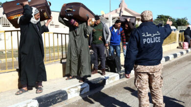 Egyptians walk carrying their belongings in Libya