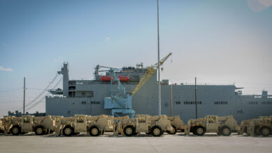 Army vehicles wait to be loaded onto the USNS Watkins at Joint Base Charleston, SC