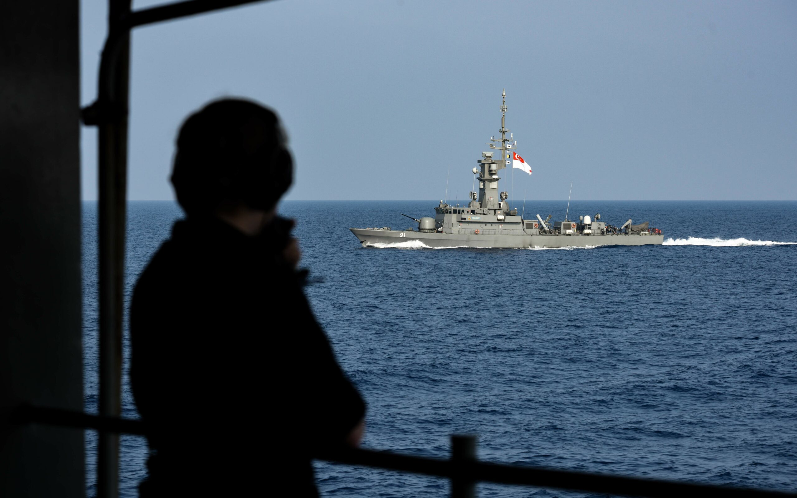 180406-N-GP724-2430 SOUTH CHINA SEA (April 6, 2018) Seaman Yara Schmidt watches as the Republic of Singapore Navy Victory-class corvette RSS Valiant (PGG 91) sails alongside the aircraft carrier USS Theodore Roosevelt (CVN 71). Theodore Roosevelt is currently underway for a regularly scheduled deployment in the U.S. 7th Fleet area of operations in support of maritime security operations and theater security cooperation efforts. (U.S. Navy photo by Mass Communication Specialist 3rd Class Alex Perlman/Released)
