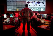A cyber warfare operations officer watches members of the 175th Cyberspace Operations Group analyze log files and provide a cyber threat update.