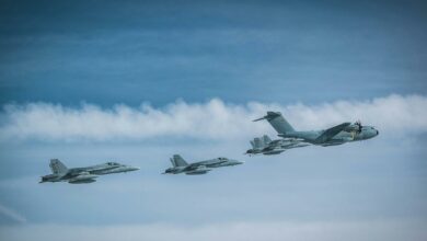 A German Air Force Airbus A400M Atlas flies in formation with four Finnish F/A-18 fighters.