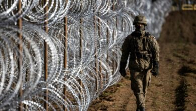 A Polish soldier walks along the razor-wire fence along the country's border with Russia