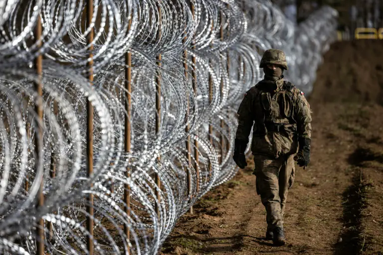 A Polish soldier walks along the razor-wire fence along the country's border with Russia