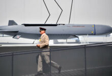 A member of the military walks past an MBDA Storm Shadow/Scalp missile at the Farnborough Airshow, south west of London