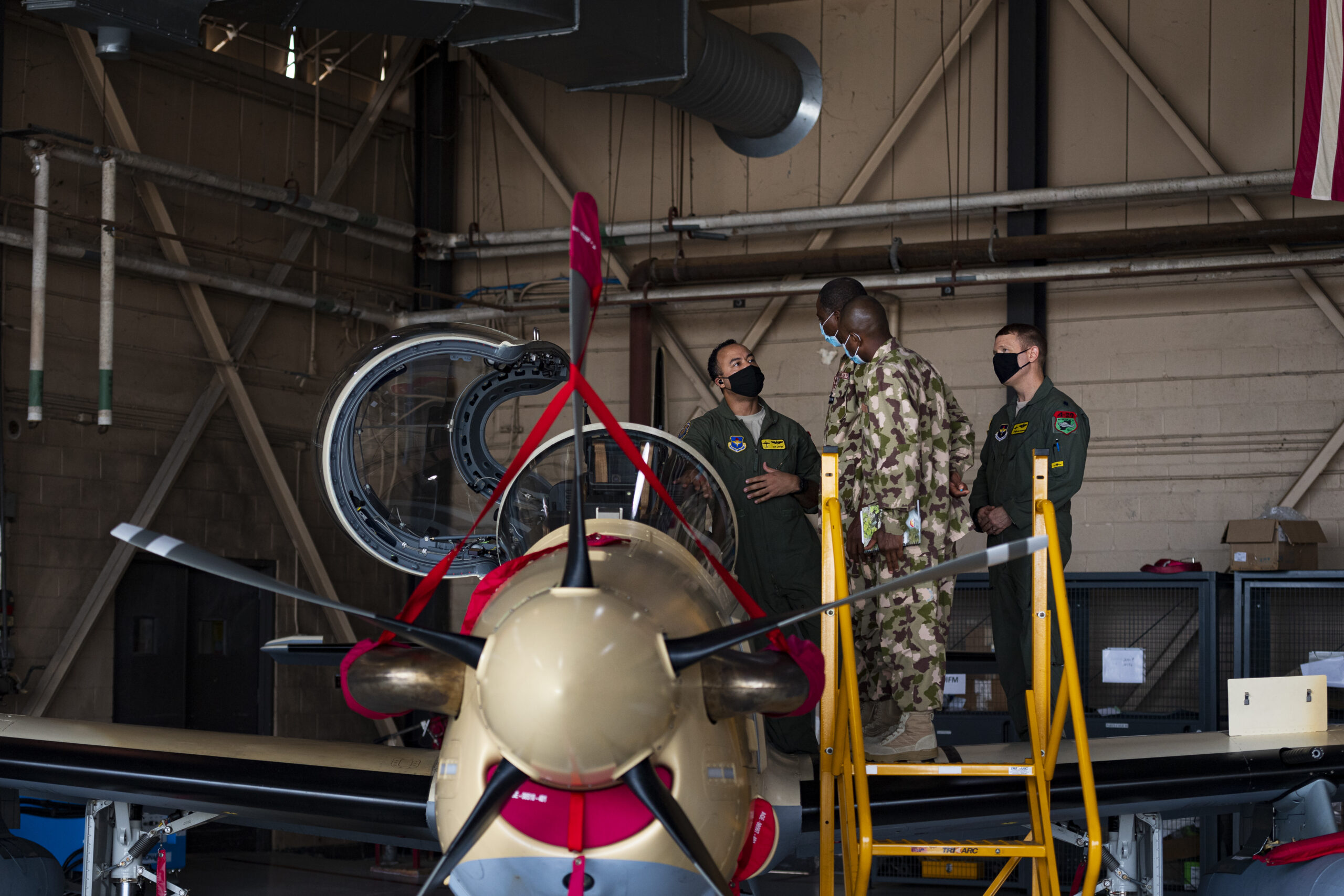 U.S. Air Force Lt. Col. Aaron Jones, left, 81st Fighter Squadron director of operations, explains the operation of an A-29 Super Tucano to Nigerian Air Force Air Vice Marshall Sule Lawal and NAF Group Captain Abdullahi Abu, Nigerian A-29 program foreign liaison officers, Oct. 6, 2020, at Moody Air Force Base, Georgia. The 81st FS conducts combat training for NAF pilots and maintainers in the A-29 Super Tucano. Foreign liaison officers with the NAF, along with representatives of the Air Force Life Cycle Management Center, Air Force International Affairs, the Air Force Security Assistance and Training Squadron, and the Nigerian A-29 program, visited the 81st FS to discuss the future of the program and meet with students. (U.S. Air Force photo by Senior Airman Hayden Legg)