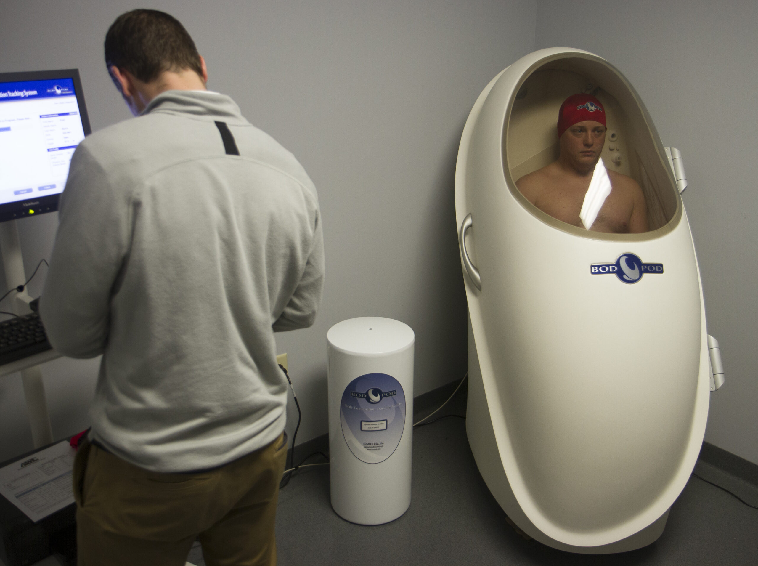 Sgt. Evan Myers with the 120th Public Affairs Detachment sits inside the BodPod® body composition measurement system as Logan Blackwell, a health educator at the Army Wellness Center, conducts a health assessment at Camp Atterbury May 8. The Bod Pod is a tool used to accurately exam an individuals height, weight and body fat percentage. (U.S. Army National Guard photo by Spc. Hannah Clifton)