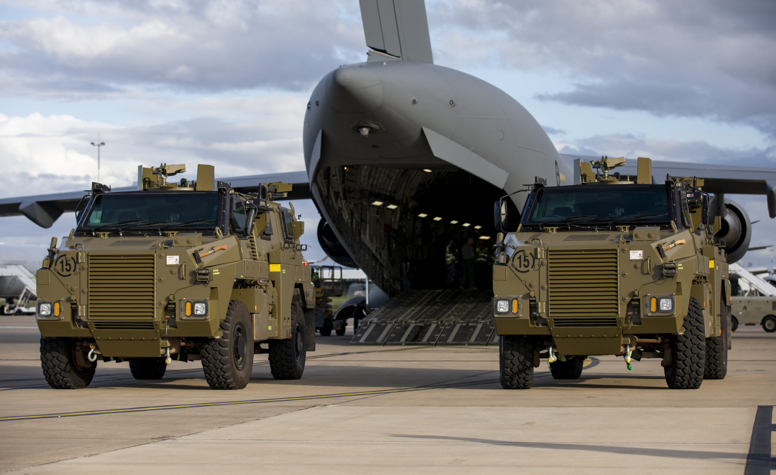 Two Bushmaster protected mobility vehicles bound for Ukraine wait to be loaded onto a C-17A Globemaster III aircraft at RAAF Base Amberley, Queensland. *** Local Caption *** The Australian Government has provided further support to the Government of Ukraine by gifting 20 Bushmaster Protected Mobility Vehicles, including two ambulance variants, to aid the Government of Ukraines response to Russias unrelenting and illegal aggression. Australias response follows a direct request from President Zelenskyy during his address to a joint sitting of the Parliament of Australia on 31 March 2022. The Bushmaster Protected Mobility Vehicle was built in Australia to provide protected mobility transport, safely moving soldiers to a battle area prior to dismounting for close combat. The Bushmaster Protected Mobility Vehicle is well suited to provide protection to the Ukrainian Armed Forces soldiers and Ukrainian civilians against mines and improvised explosive devices, shrapnel from artillery and small arms fire. The vehicles have been painted olive green to suit the operating environment. Additionally, a Ukrainian flag is painted on either side with the words United with Ukraine stencilled in English and Ukrainian to acknowledge our commitment and support to the Government and people of Ukraine. The ambulances will have the traditional red cross emblem. The Bushmaster Protected Mobility Vehicles will be fitted with radios, a global positioning system and additional bolt-on armour increasing their protection.