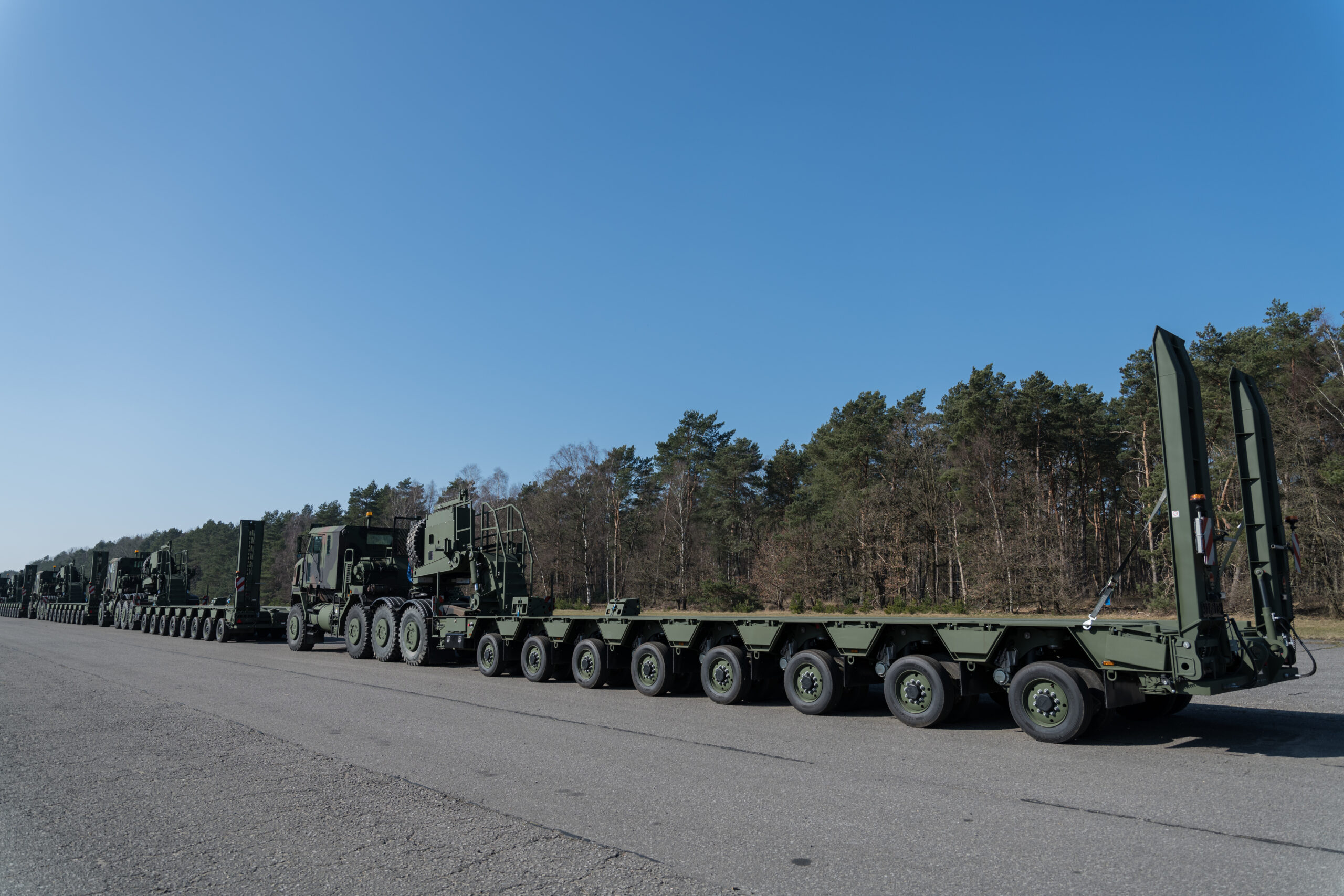 U.S. Army Enhanced Heavy Equipment Transporter Systems line up for a convoy, in a staging area of the Army Prepositioned Stock-2 site, in Zutendaal, Belgium, Mar. 09, 2022. Army Prepositioned Stocks is a U.S. Department of the Army program in which equipment sets are stored around the globe for use when a combatant commander requires additional capabilities. The U.S. Army has seven APS regions and APS-2 is designated for Europe. APS sites reduce deployment timelines, improve deterrence capabilities, and provide additional combat power for contingency operations. (U.S. Army photo by Pierre-Etienne Courtejoie)