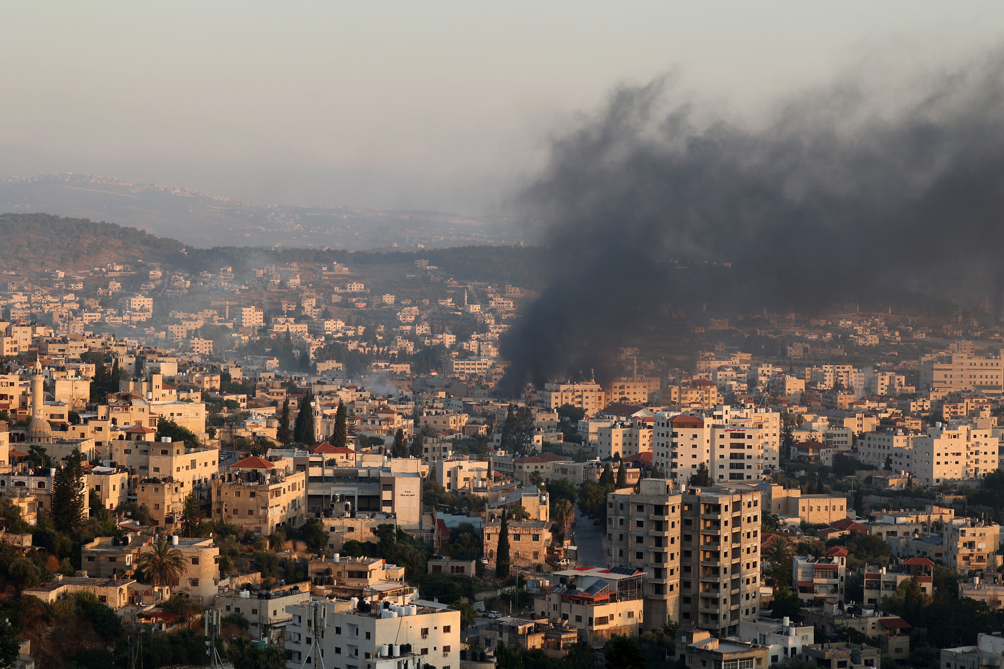 Smoke billows from houses inside the Jenin refugee camp in the northern West Bank city of Jenin
