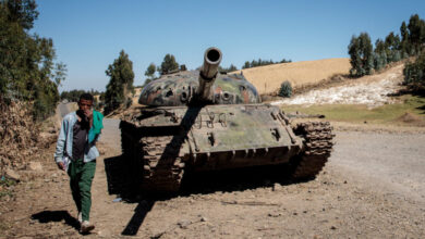 A person walks besides an abandoned tank in Ethiopia