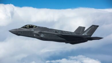 An F-35A Lightning II of the Australian Defence Force is seen mid-flight. Clouds are seen in the background, in the same elevation as the aircraft.